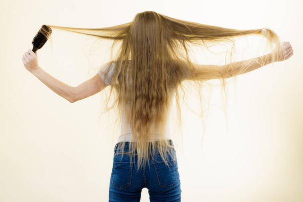 Blonde girl brushing her long hair - Фото, изображение