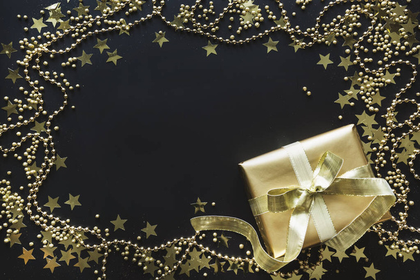 Border of luxury golden gift box on black background. Christmas present. Flat lay. Top view. Xmas. - Fotografie, Obrázek