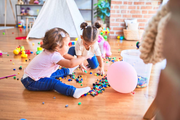 Suloiset pikkulapset leikkivät rakennuspalikoilla lelu päiväkodissa
 - Valokuva, kuva