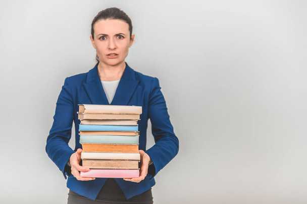 Young teacher carrying a stack of heavy books, frowning her face. - Foto, Imagen