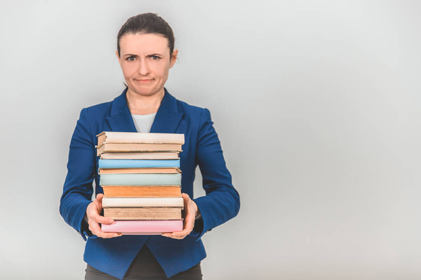 Young teacher carrying a stack of heavy books, frowning her face. - Photo, Image