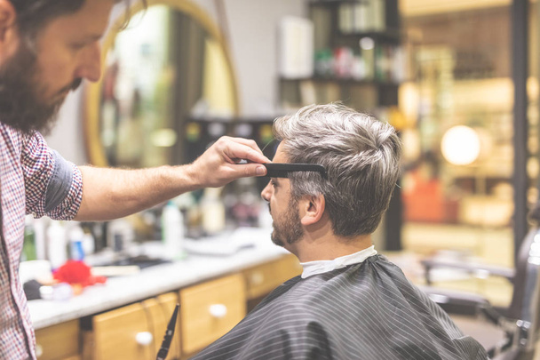 Man in barber chair, hairdresser styling his hair. - Photo, Image