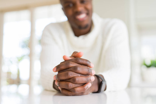 Zblízka překřížené ruce africké člověka nad stůl s úsměvem - Fotografie, Obrázek