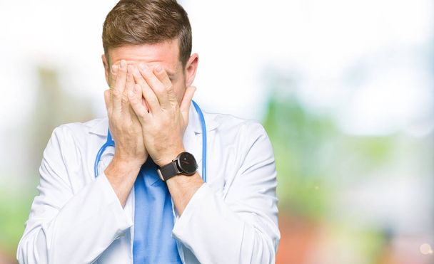 Pohledný doktor muž uniformě zdravotní izolované pozadí se smutným výrazem pokrývající obličej rukama a plakat. Koncept deprese. - Fotografie, Obrázek