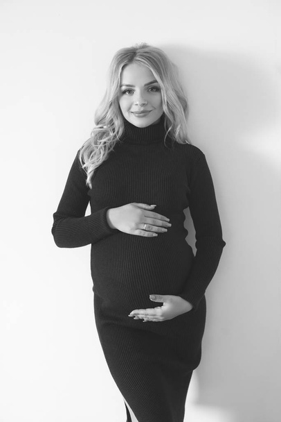 Attractive young woman with blond pregnant hair in a dark dress. Healthy happy pregnancy - Фото, зображення