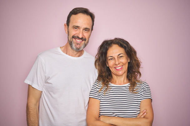 Beau couple d'âge moyen ensemble debout sur fond rose isolé heureux visage souriant avec les bras croisés regardant la caméra. Personne positive
. - Photo, image