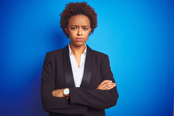 Mujer ejecutiva de negocios afroamericana sobre fondo azul aislado escéptico y nervioso, desaprobando la expresión en la cara con los brazos cruzados. Persona negativa
. - Foto, Imagen