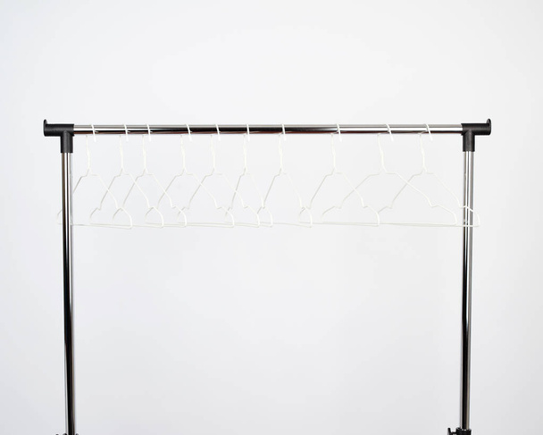 Leere weiße Metallbügel hängen an einer Chromstange - Foto, Bild
