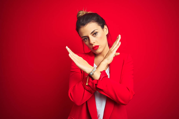 Young beautiful business woman standing over red isolated background Rejection expression crossing arms doing negative sign, angry face - Photo, Image