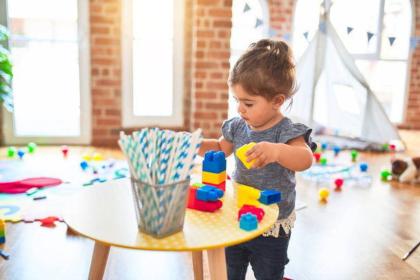 Beautiful toddler playing with building blocks toys at kindergarten - Foto, Imagem
