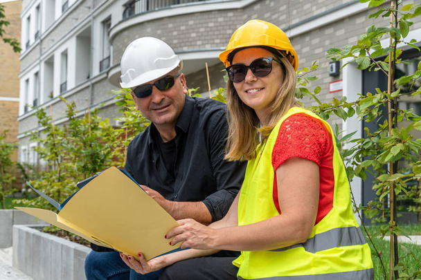 Mužští a ženské stavební inženýři sedí venku analyzovat projekty a kancelářské plány - Fotografie, Obrázek