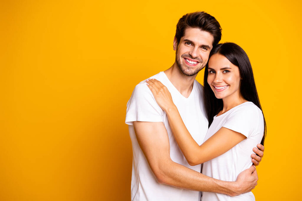 Happy together. Photo of amazing pair in love hugging wear casual white t-shirts isolated yellow color background - Fotó, kép