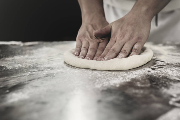 Chef hands knead the dough for pizza preparation. - Fotoğraf, Görsel