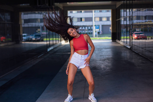 Young brunette woman dancing and shaking her hair in arch of building. - Photo, Image