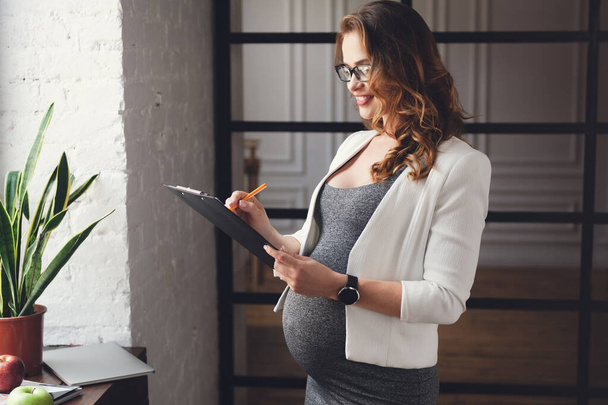 Zwangere volwassen zakenvrouw werken op kantoor - Foto, afbeelding