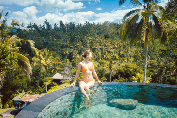 Жінка насолоджується відпусткою в басейні в тропіках
 - Фото, зображення