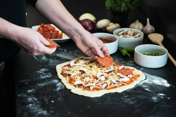 Frau bereitet zu Hause Pizza zu - Foto, Bild