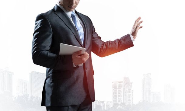 Business advisor standing and pointing copy space. Business presentation and marketing. Man in formal wear on background foggy cityscape. Financial specialist with raised hand promotion mockup - Photo, image