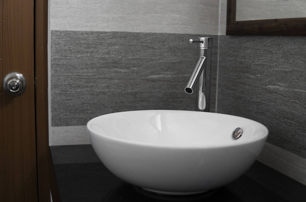 Bathroom interior with white round sink and chrome faucet in a modern bathroom. - Fotó, kép