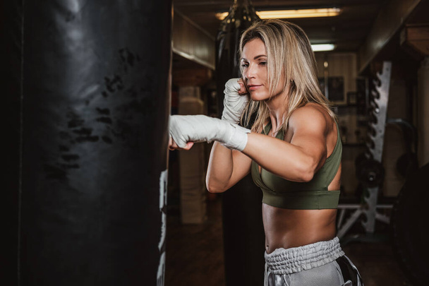 Портрет женщины-боксера на тренировке с боксерской грушей
 - Фото, изображение