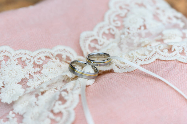 Nahaufnahme von goldenen Eheringen auf dekorativem rosa Ringkissen - Foto, Bild