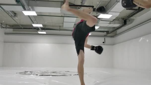 Movimento lento: O lutador ataca com uma volta durante a rotação da perna. Treinador segura patas para treinamento de kickboxer antes da luta
 - Filmagem, Vídeo