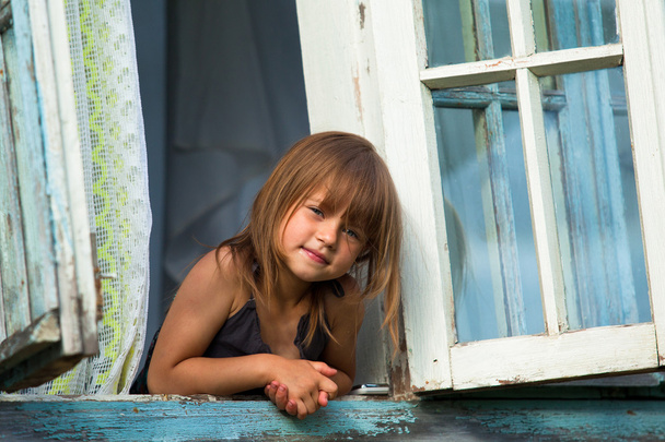 κοριτσάκι να κοιτάζει έξω από το παράθυρο αγροτικό σπίτι. - Φωτογραφία, εικόνα