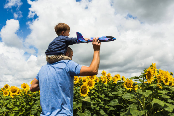 Père et fils jouant avec un avion jouet près du champ de tournesol
 - Photo, image
