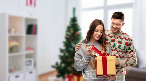 happy couple in christmas sweaters with gift box - Fotó, kép