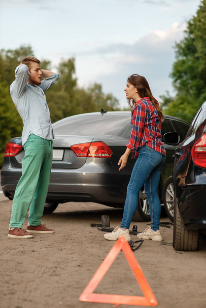 Car accident on road, man and woman are sorted out. Automobile crash, emergency stop sign. Broken automobile or damaged vehicle, auto collision on highway - Fotoğraf, Görsel