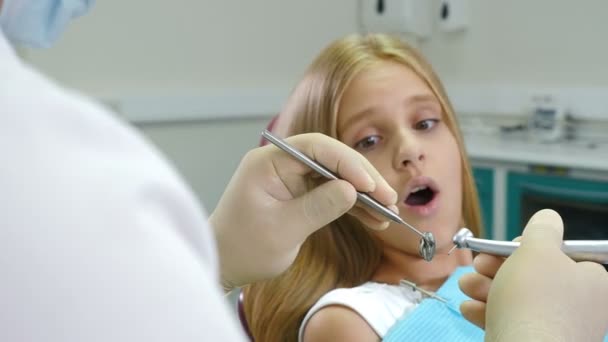 Pieni pelokas tyttö hammaslääkärillä. Terveys ja hammashoito. Lähikuva kuva hammaslääkäri pora ja peili käsissä. 4K kuvamateriaali
. - Materiaali, video