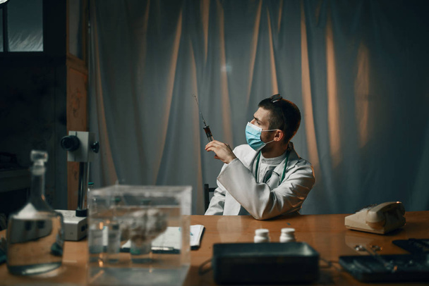 Mannelijke psychiater in masker met injectiespuit met een kalmerend, mentaal ziekenhuis. Arts in de kliniek voor geesteszieken - Foto, afbeelding