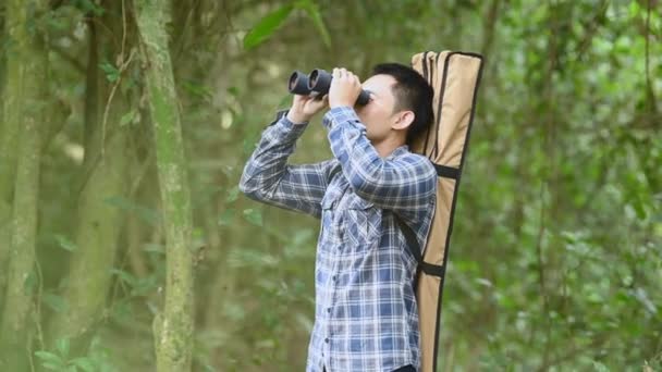 Ο άνθρωπος με τα κιάλια τηλεσκόπιο στο δάσος αναζητούν προορισμό ως χαμένους ανθρώπους ή προβλέψιμο μέλλον. Ο τρόπος ζωής και η ψυχαγωγία των ανθρώπων. Φύση και σακίδια ταξιδεύοντας σε ζούγκλα φόντο - Πλάνα, βίντεο