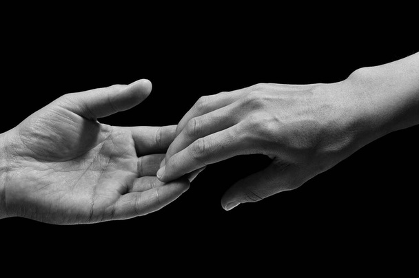 Zwart-wit foto van twee handen op het moment van uit elkaar gaan. Het concept van uit elkaar gaan. Op zwarte geïsoleerde achtergrond. Afbeelding. - Foto, afbeelding