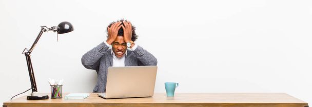 young black businessman feeling stressed and anxious, depressed and frustrated with a headache, raising both hands to head on a desk - Photo, Image