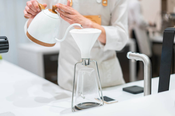 process of preparation black coffee in chemex pour over coffee maker in bright modern cafe. Alternative ways of brewing coffee. - Foto, Imagem