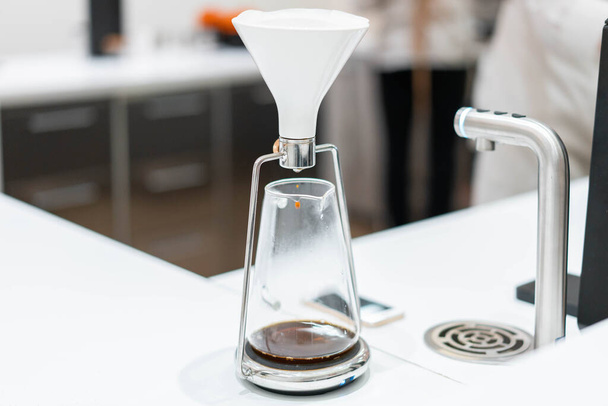 process of preparation black coffee in chemex pour over coffee maker in bright modern cafe. Alternative ways of brewing coffee. - Foto, Bild