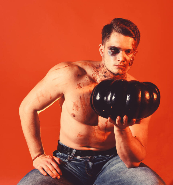 Man with scary face and sexy torso on orange background. - Foto, Imagen