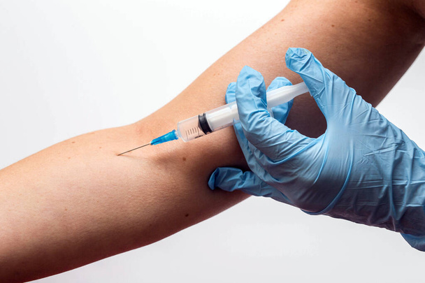Medico o infermiere che somministrano l'iniezione di vaccino nel braccio ad un paziente isolato su bianco
 - Foto, immagini