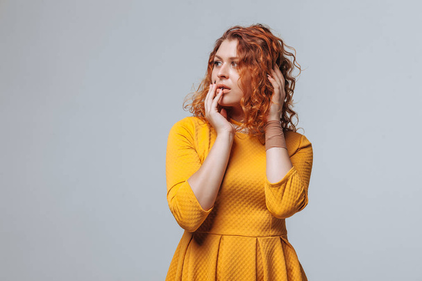 Redhaired curly menina pensa em um fundo cinza claro
 - Foto, Imagem
