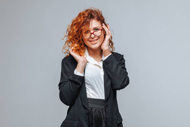 Red-haired woman in a suit and touches glasses - Fotografie, Obrázek