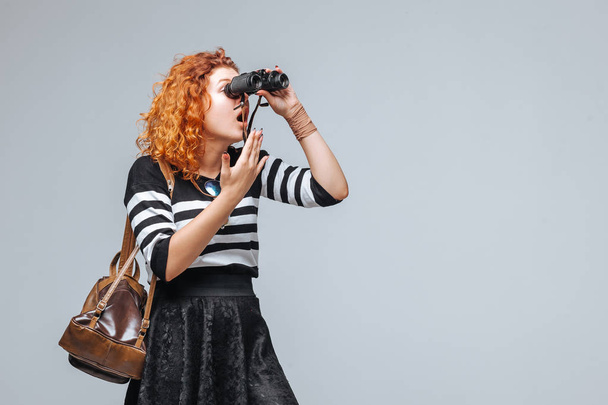 rojo cabeza turista chica looks a través de binoculares
 - Foto, Imagen