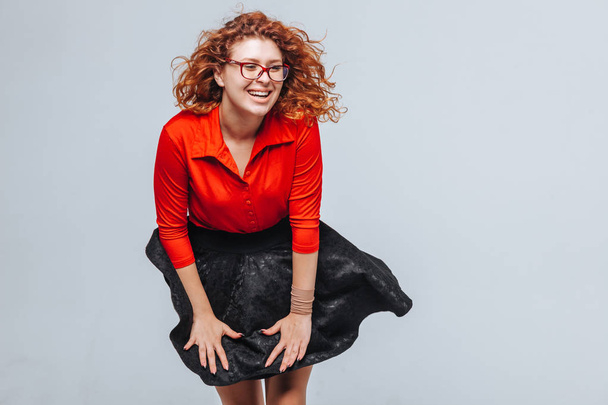 The wind lifts her skirt redhead girl in red blouse - 写真・画像