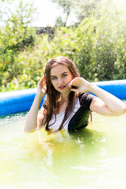 Güzel kadın model uzun akşam önlük giymiş, havuzda yatıyor ve sensually poz veriyor - Fotoğraf, Görsel