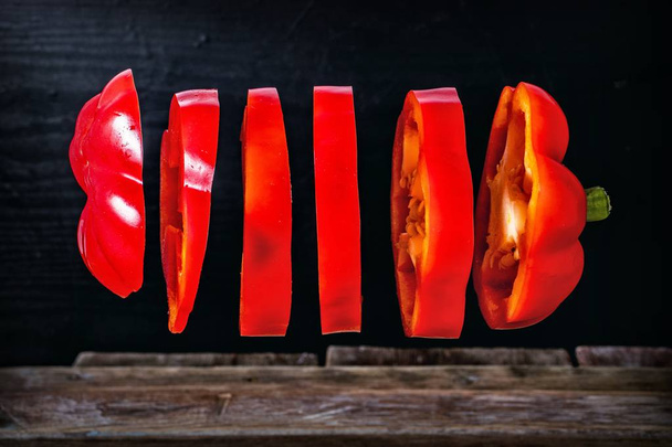 木のテーブルの上で赤唐辛子をスライスし - 写真・画像