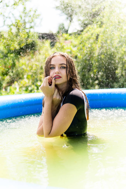 Beautiful female model dressed in long evening gowns, lies in the pool and sensually poses - 写真・画像