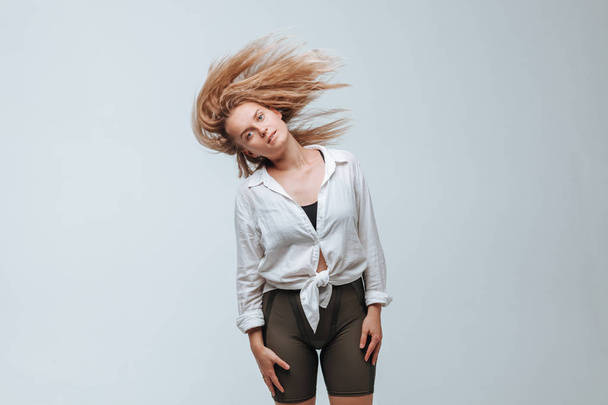 Girl shakes her hair on a gray background - Fotó, kép