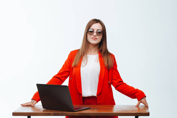 Sexy girl in a red jacket working at the computer on a white bac - Фото, зображення