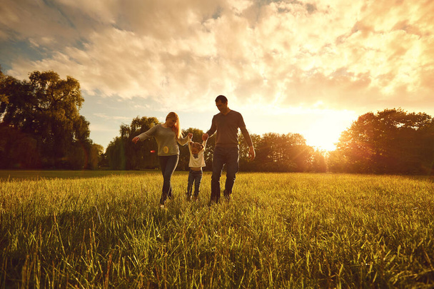 Happy family walks on the park at sunset. - Φωτογραφία, εικόνα