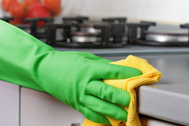 Close-up of a hand in a protective glove holding a rag. Cleaning the kitchen - Фото, изображение